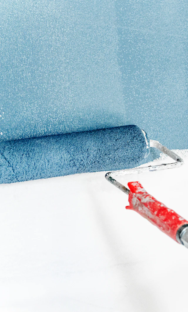 Rodillo aplicando pintura azul sobre una pared blanca