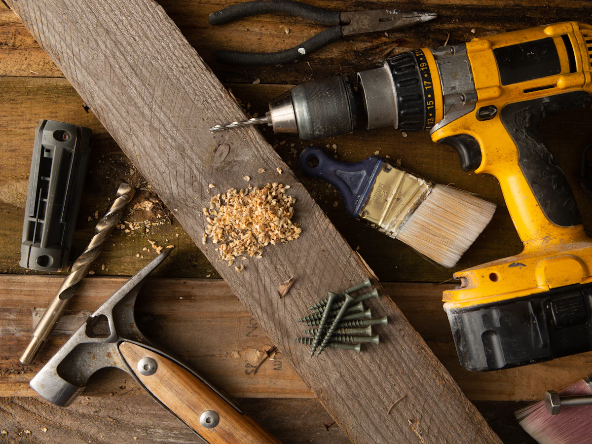Taladro, brochas y tornillos sobre un banco de madera